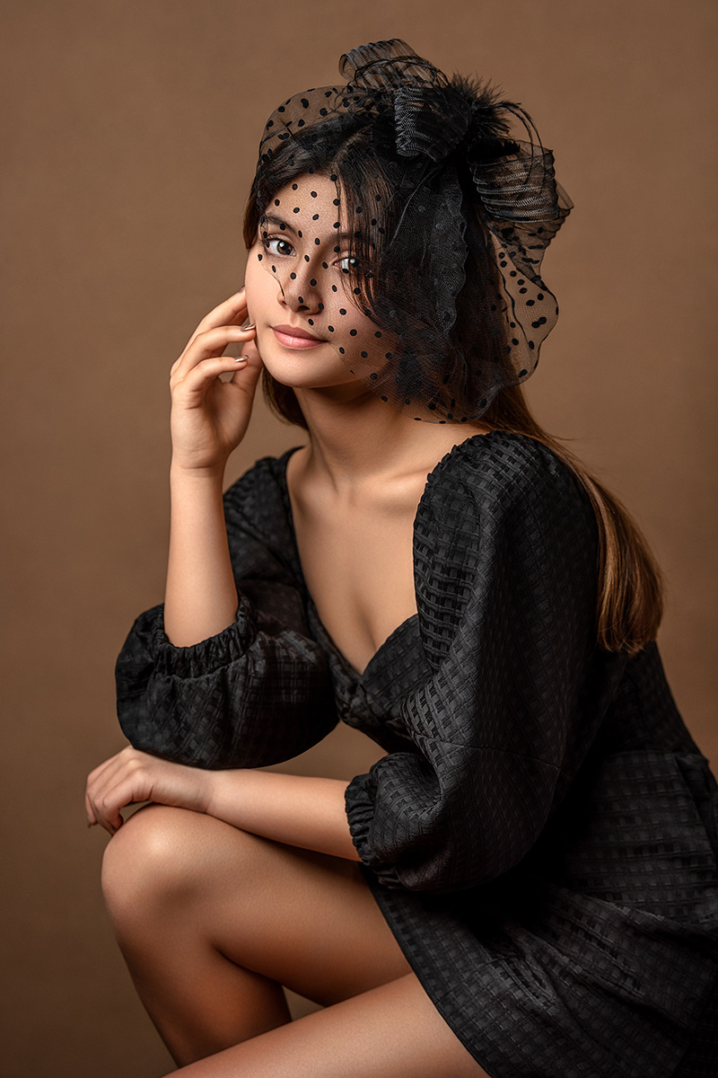 A fine art portrait featuring a teenage girl model in a black dress and vintage hat with a veil, captured by Houston child photographer Tatyana Sokolova