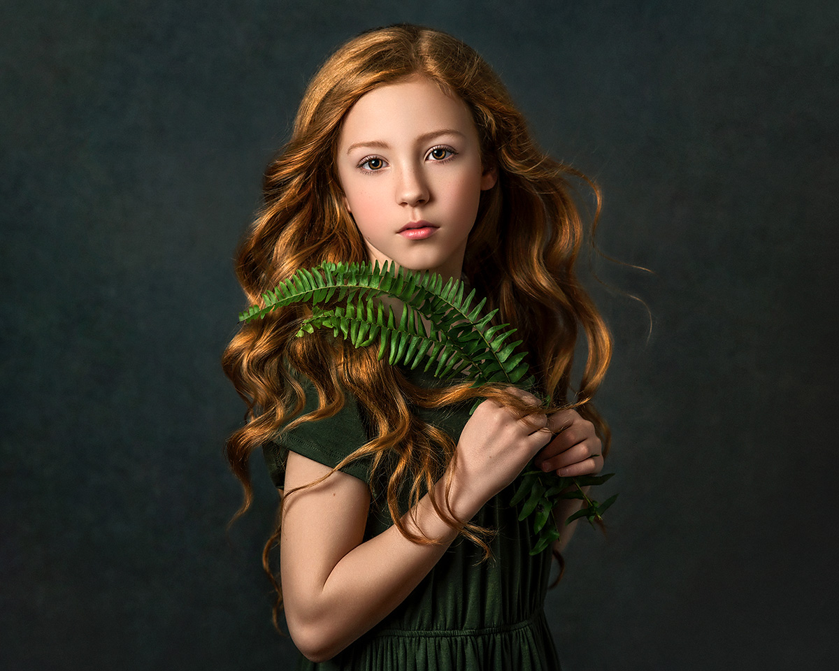 A fine art portrait showcasing the beauty of a girl with gorgeous red hair, dressed in green and holding a fern, created by Tatyana Sokolova